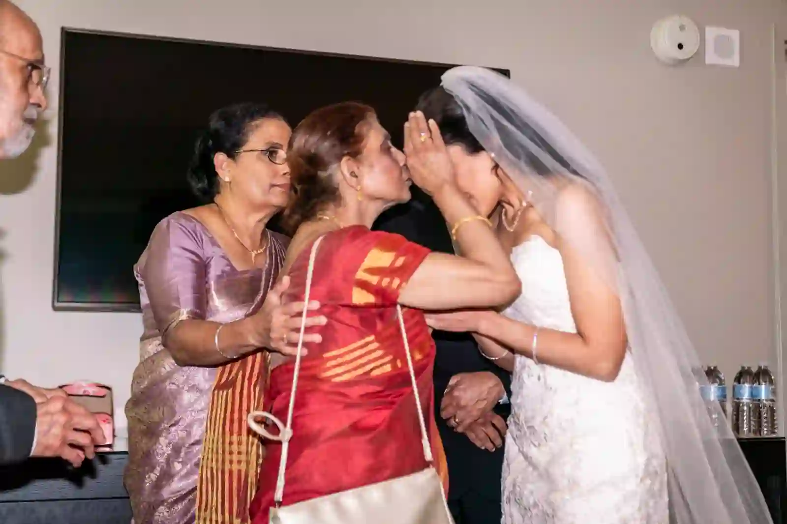 Bride embracing her mother and grandmothers in saris before the ceremony