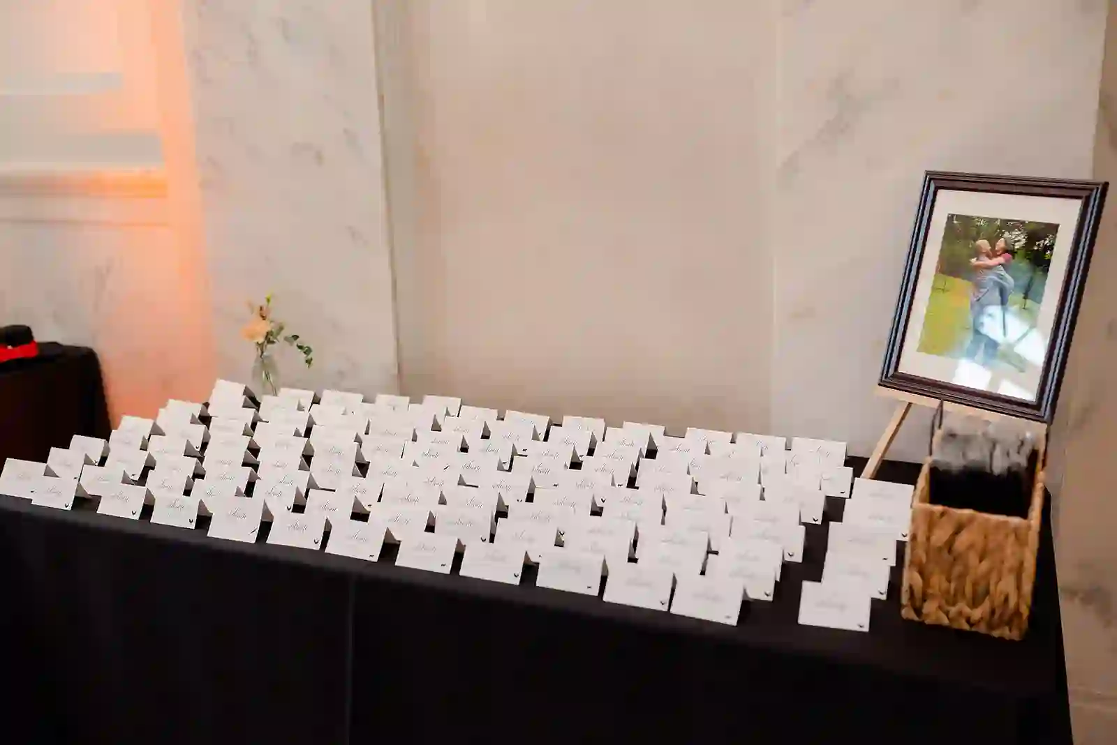 Reception escort card display with calligraphy place cards and a framed couple's portrait