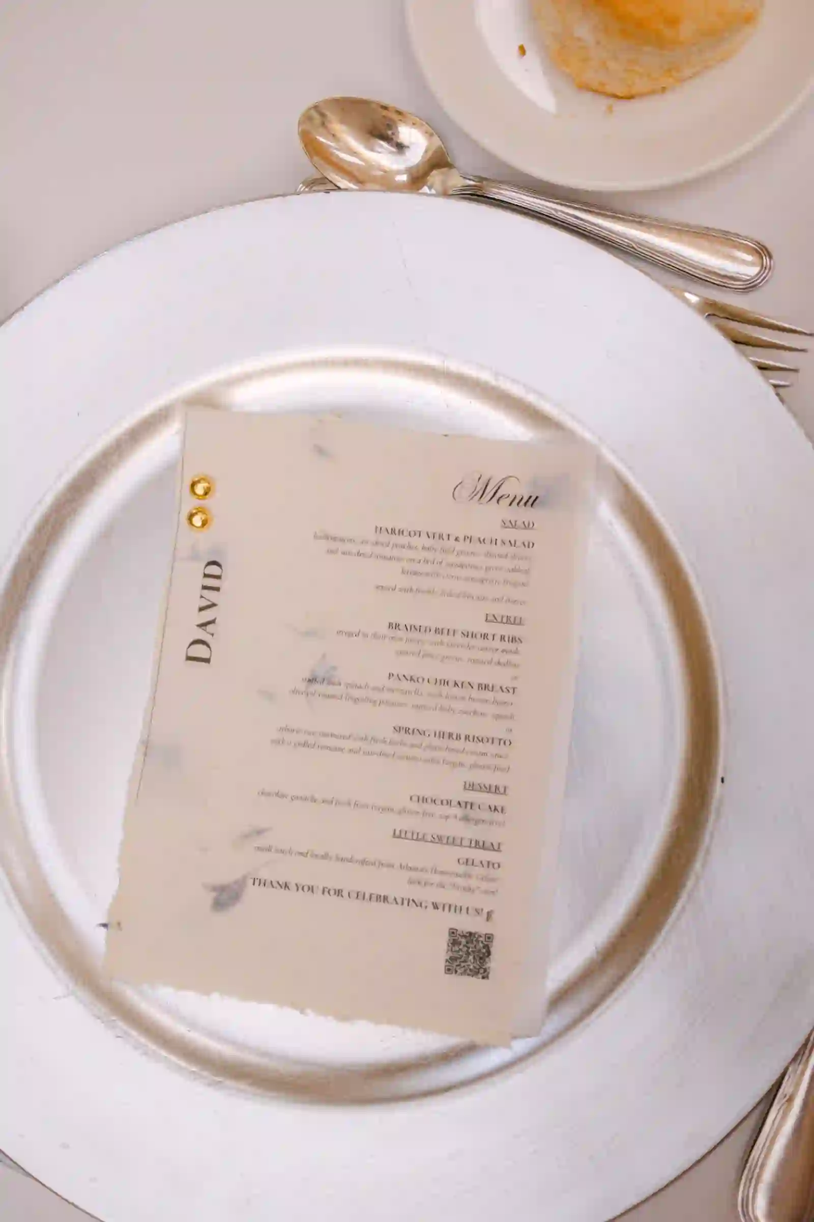 Handmade petal-pressed dinner menu and gold-leaf place card on a silver charger