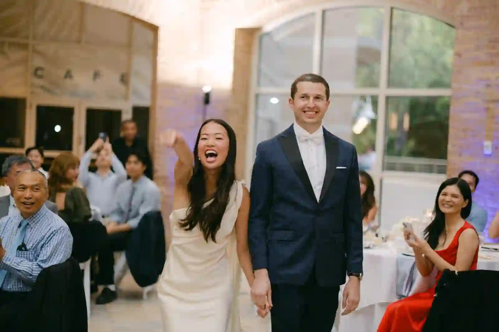 Grand entrance of the bride and groom into the reception, surrounded by cheering guests