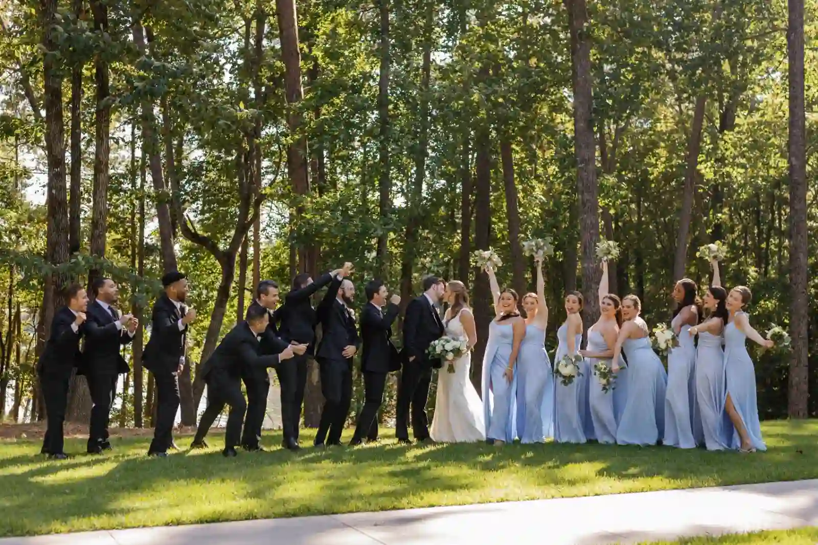 Wedding party cheering as the couple shares a kiss in the pines