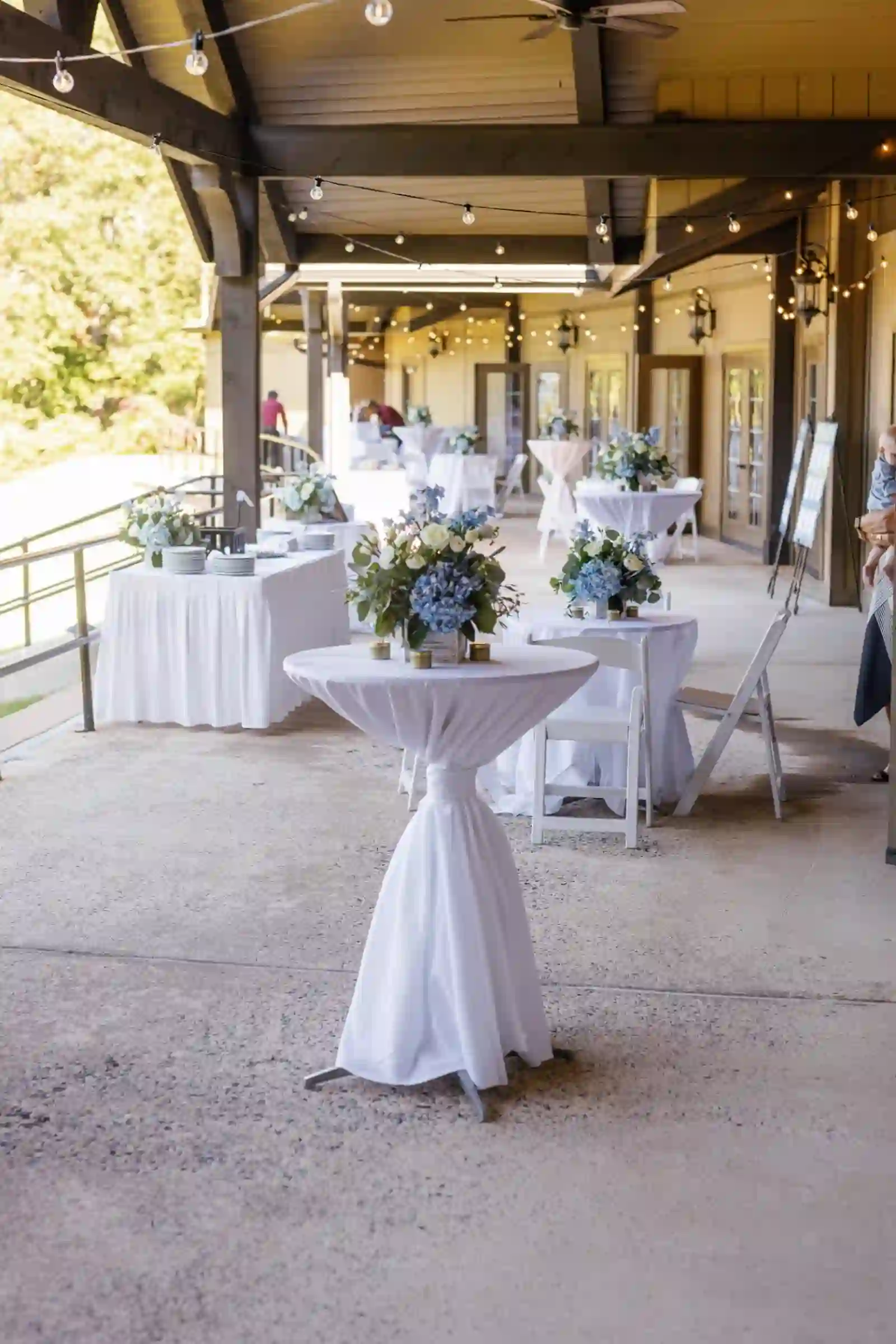 Cocktail hour under string lights with blue hydrangea arrangements