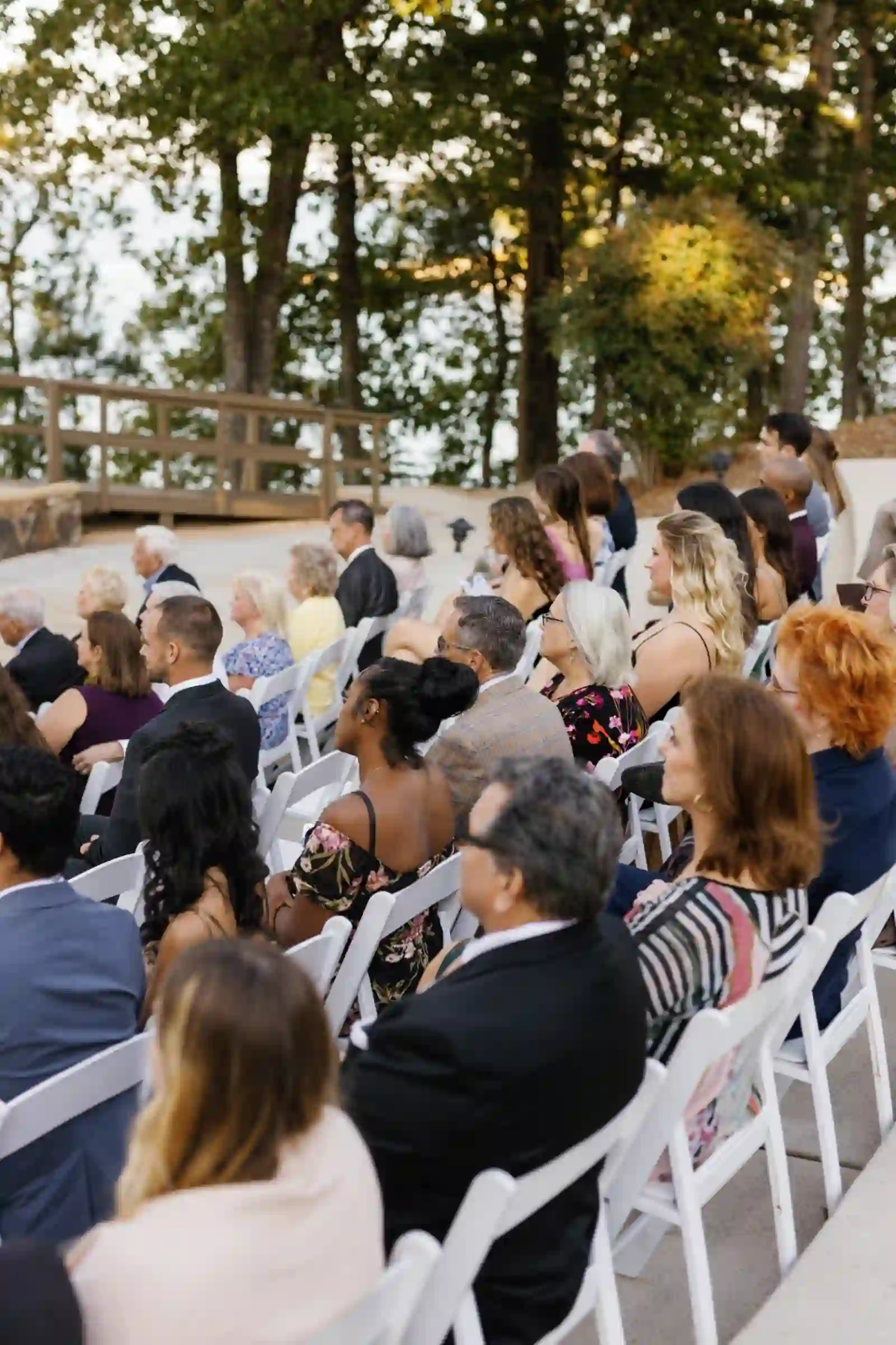 Guests seated in white chairs at the open-air lakeside ceremony