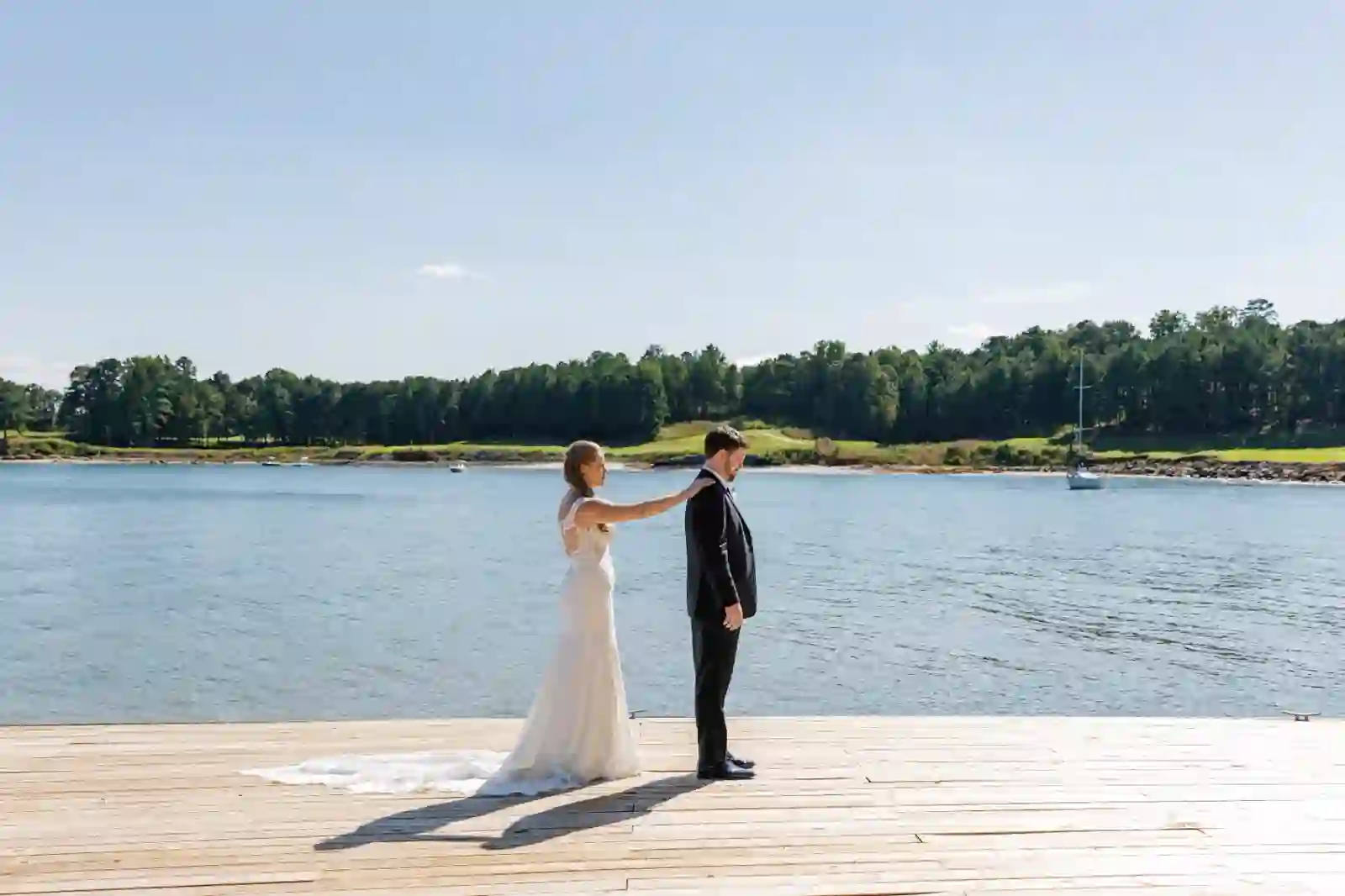 Bride and groom first look on the dock with sailboat in the distance