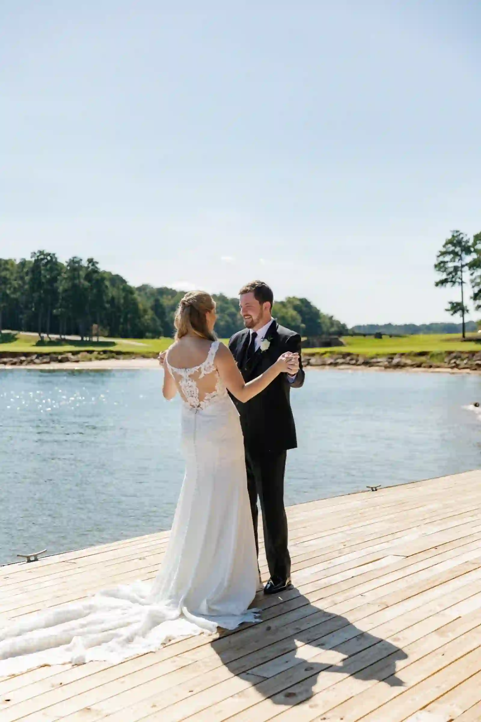 Bride and groom holding hands lakeside after the first look