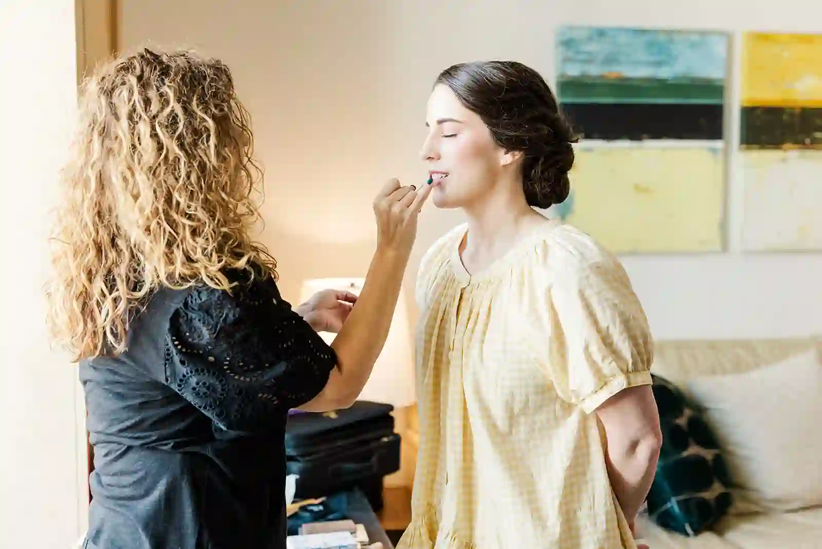 Bride having lipstick applied while getting ready in a sunlit room