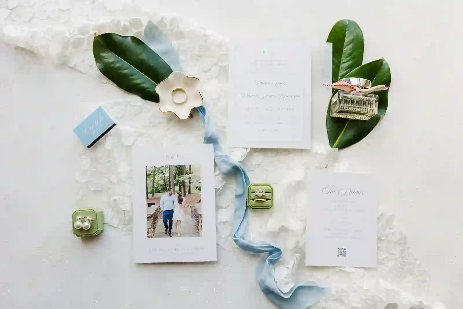 Wedding invitation suite with ring boxes, perfume, silk ribbon, and magnolia leaves