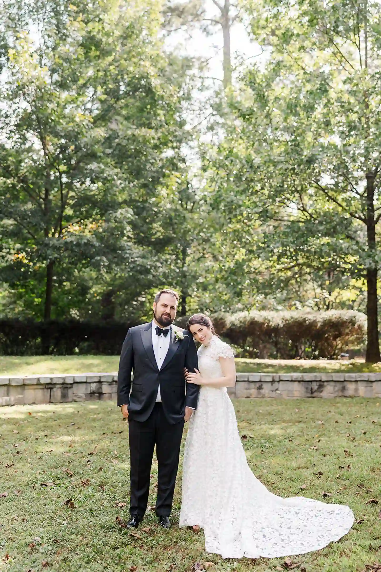 Bride leaning onto the groom during formal portraits on the lawn