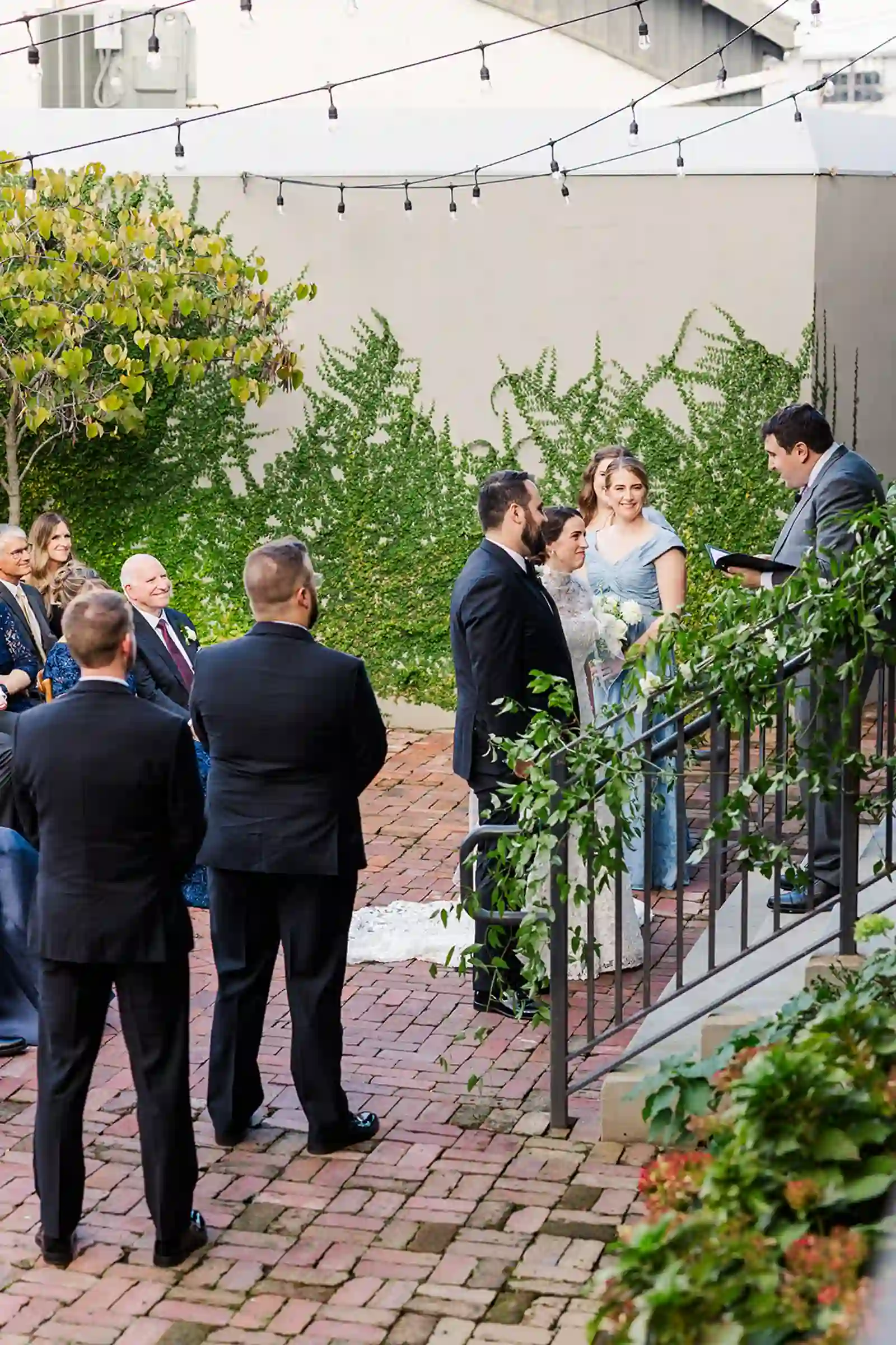 Bride and groom exchanging vows on the ceremony steps surrounded by ivy and family