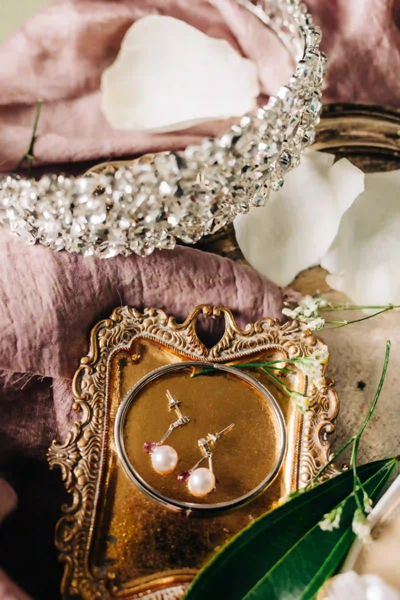 Bridal earrings and jeweled headband on a gold tray