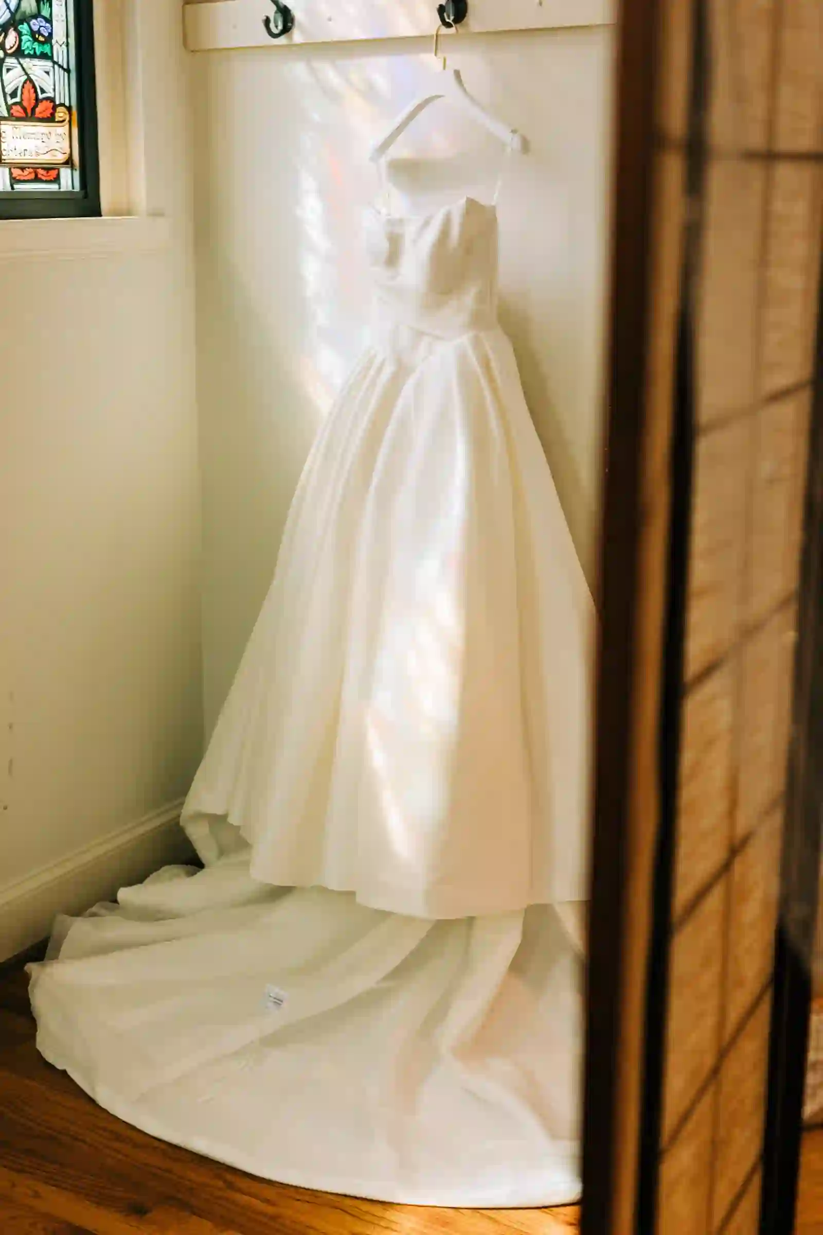Wedding dress hanging in stained-glass light