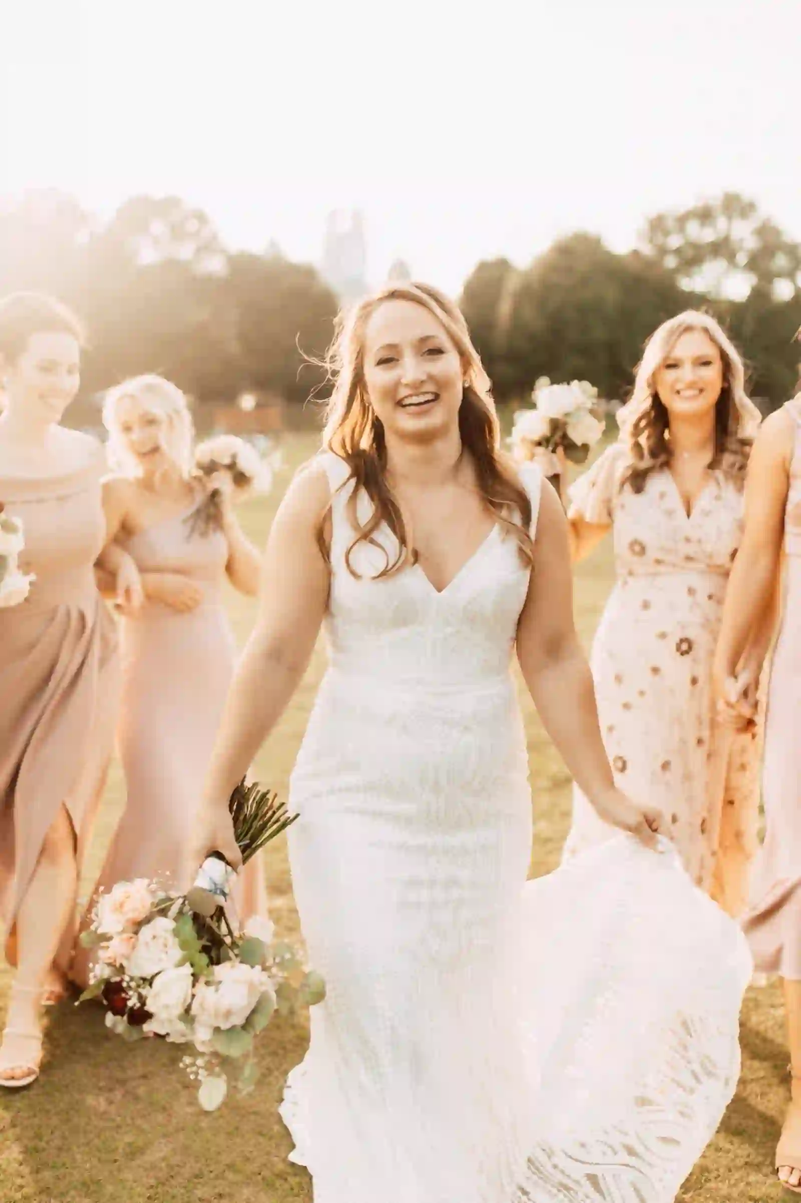 Radiant bride leading her bridesmaids in warm sunset light
