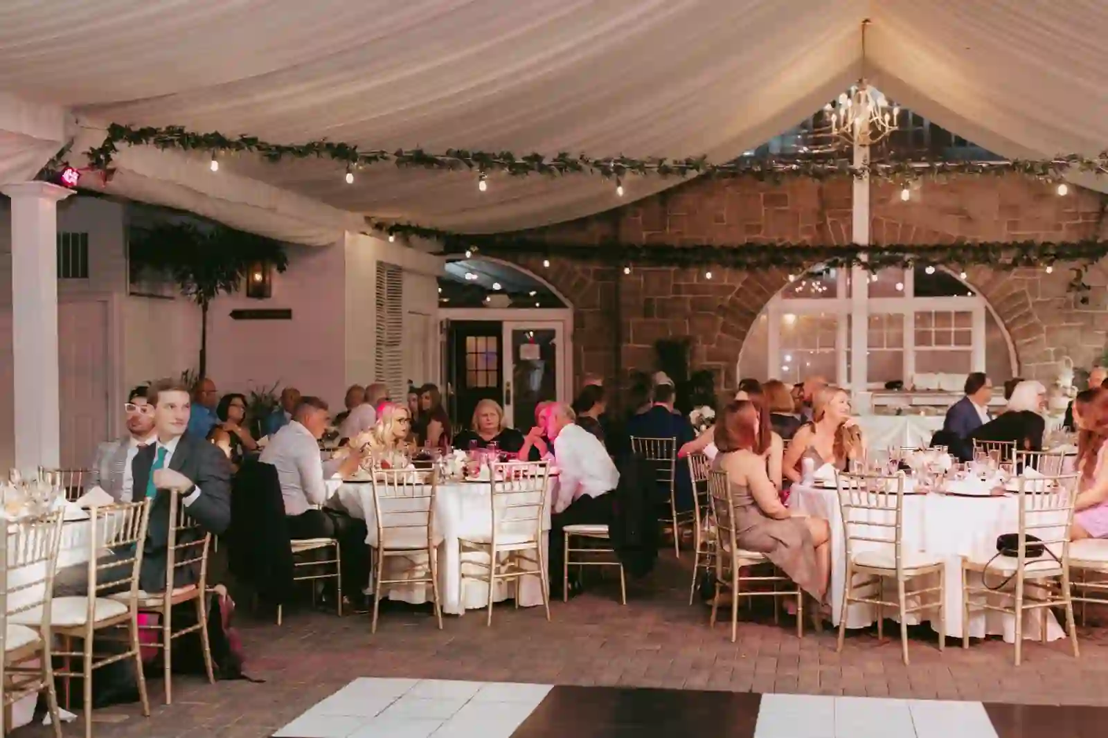 Guests gathered under the draped reception tent with greenery and lights