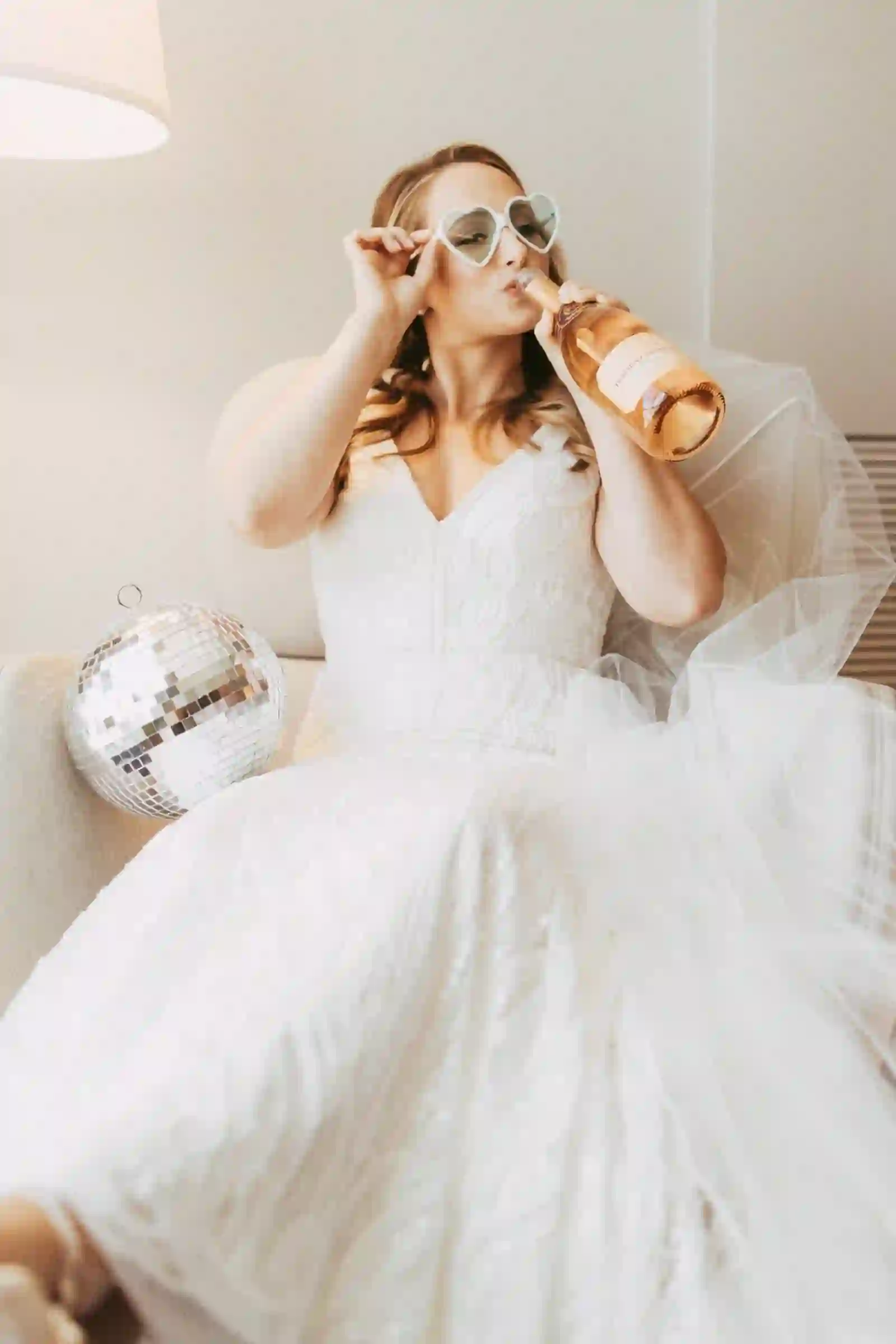 Bride in heart sunglasses sipping rosé with a disco ball